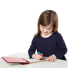 Young girl coloring with a red marker on a white background