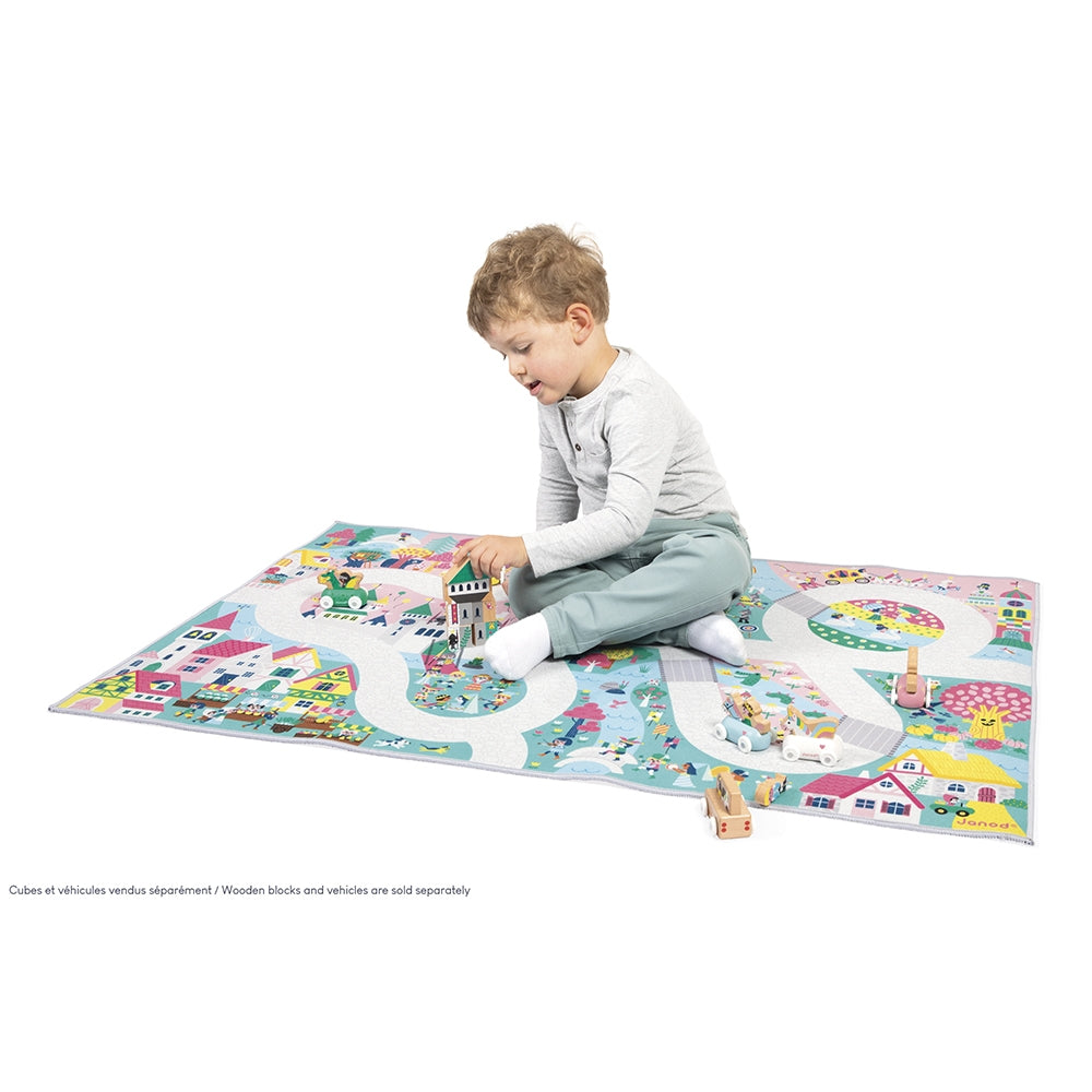 Child playing on a colorful play mat with toy cars and blocks.