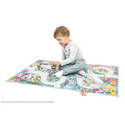 Child playing on a colorful play mat with toy cars and blocks.