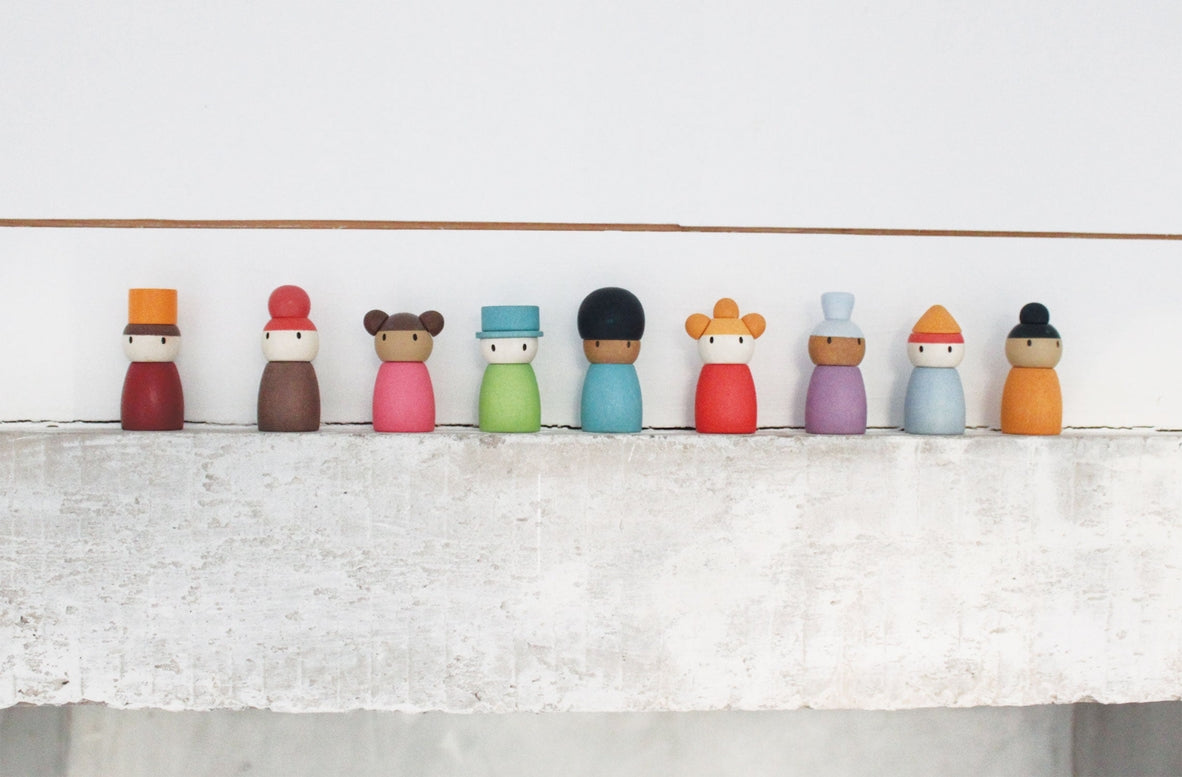 Colorful wooden peg dolls on a white surface with a light gray background