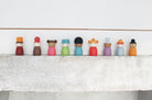 Colorful wooden peg dolls on a white surface with a light gray background