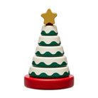 A small wooden Christmas tree toy with five stacked tiers, decorated with green wavy stripes on an off-white base, sitting on a red round base with a gold star on top, isolated on a white background.