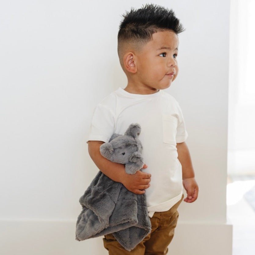 Child holding a gray plush toy against a white background