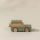 Wooden toy car with a green body and brown accents on a beige background