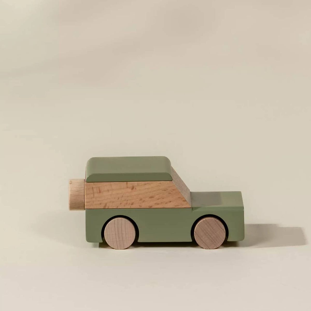 Wooden toy car with a green body and brown accents on a beige background