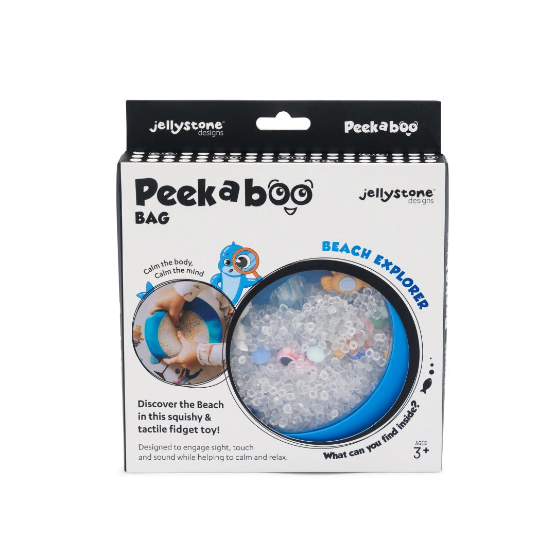 Peek a boo Bag 'Beach Explorer' sensory fidget toy in its original retail packaging by Jellystone Designs. The white box features a clear circular window showing a blue inner tray filled with clear beads and colorful sea-themed accents.