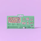 The back of a sticker sheet package on a solid lavender background. The package is mint green with a die-cut window showing various colorful food-themed stickers, including pizza, sushi, tacos, and coffee cups.