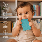A baby sitting in front of a bookshelf, holding a turquoise silicone teething toy. White text icons on the left highlight product benefits: BPA-free baby safe, soft safe silicone, teething friendly, and gift-ready packaging.