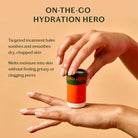 Hand holding a small cylindrical container with text about hydration and skin care on a beige background