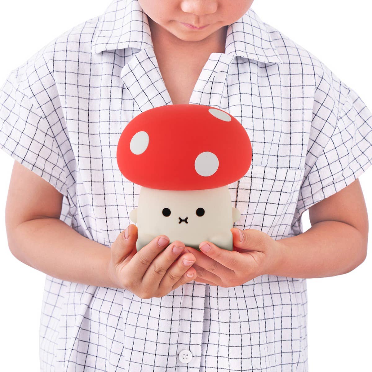 Child holding a cute mushroom-shaped phone case with a red cap and white spots.