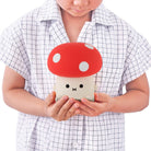 Child holding a cute mushroom-shaped phone case with a red cap and white spots.