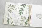 Open notebook with green leaf patterns on a gray surface