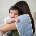 Baby being held by a person wearing a blue bib.