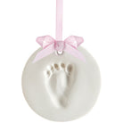 White ceramic ornament with baby footprint and pink bow on a white background.