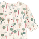 A close-up of a short-sleeve button-front top with an allover whimsical tree and bird print on a warm cream background. The print features muted green, dusty pink, and brown trees with small dark blue birds.