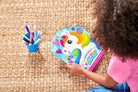 Child playing with a colorful unicorn-themed activity book on a carpeted floor.