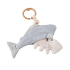 A plush trout baby rattle with a fishbone detail inside its belly, attached to a wooden ring at the top for hanging.