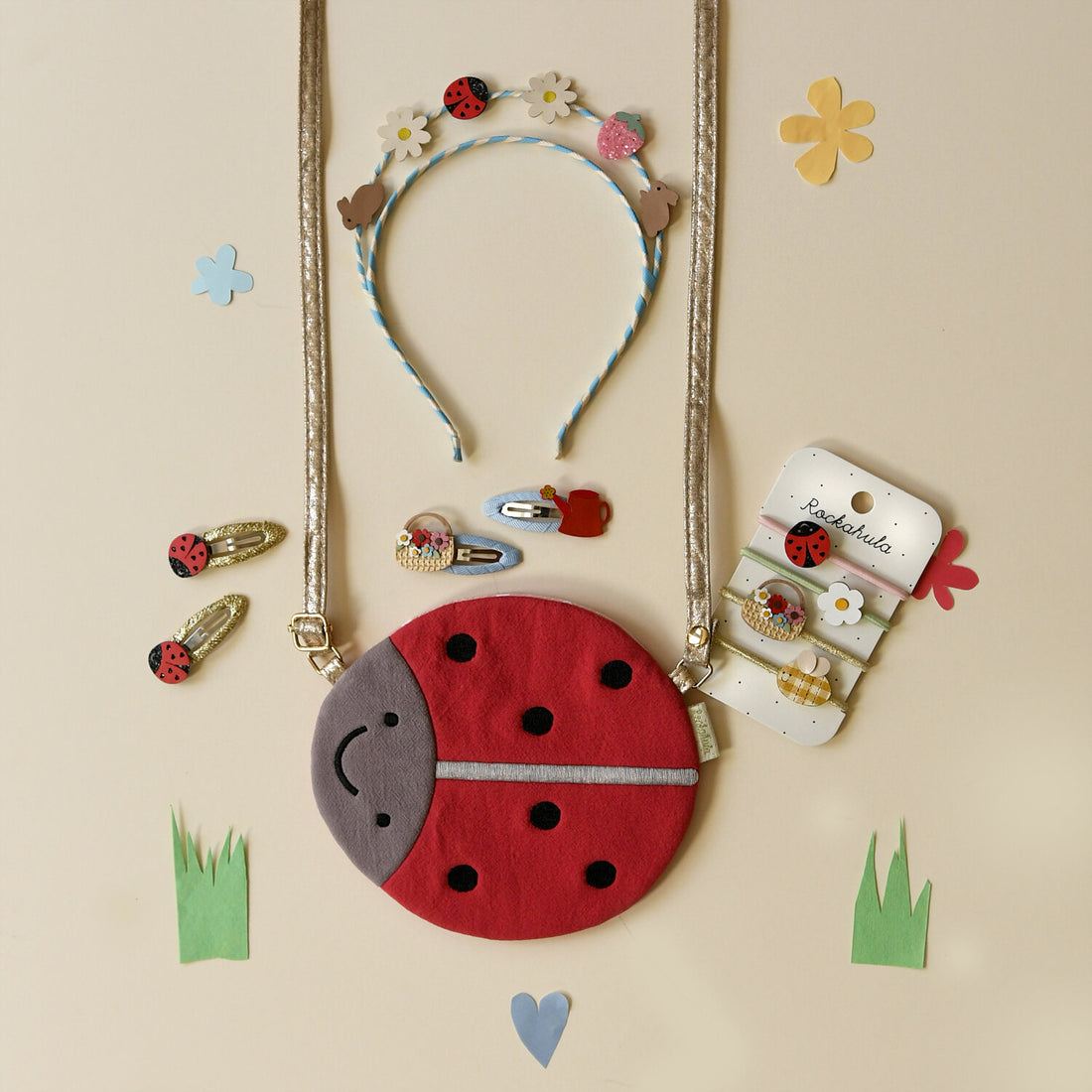Set of ladybug-themed jewelry and accessories on a beige background