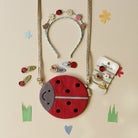 Set of ladybug-themed jewelry and accessories on a beige background