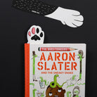 Book titled 'The Questioneers Aaron Slater and the Sneaky Snake' with paw-shaped cutouts on a black background