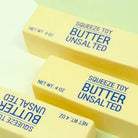 Three yellow squeeze toys labeled 'Butter Unsalted' on a light green background