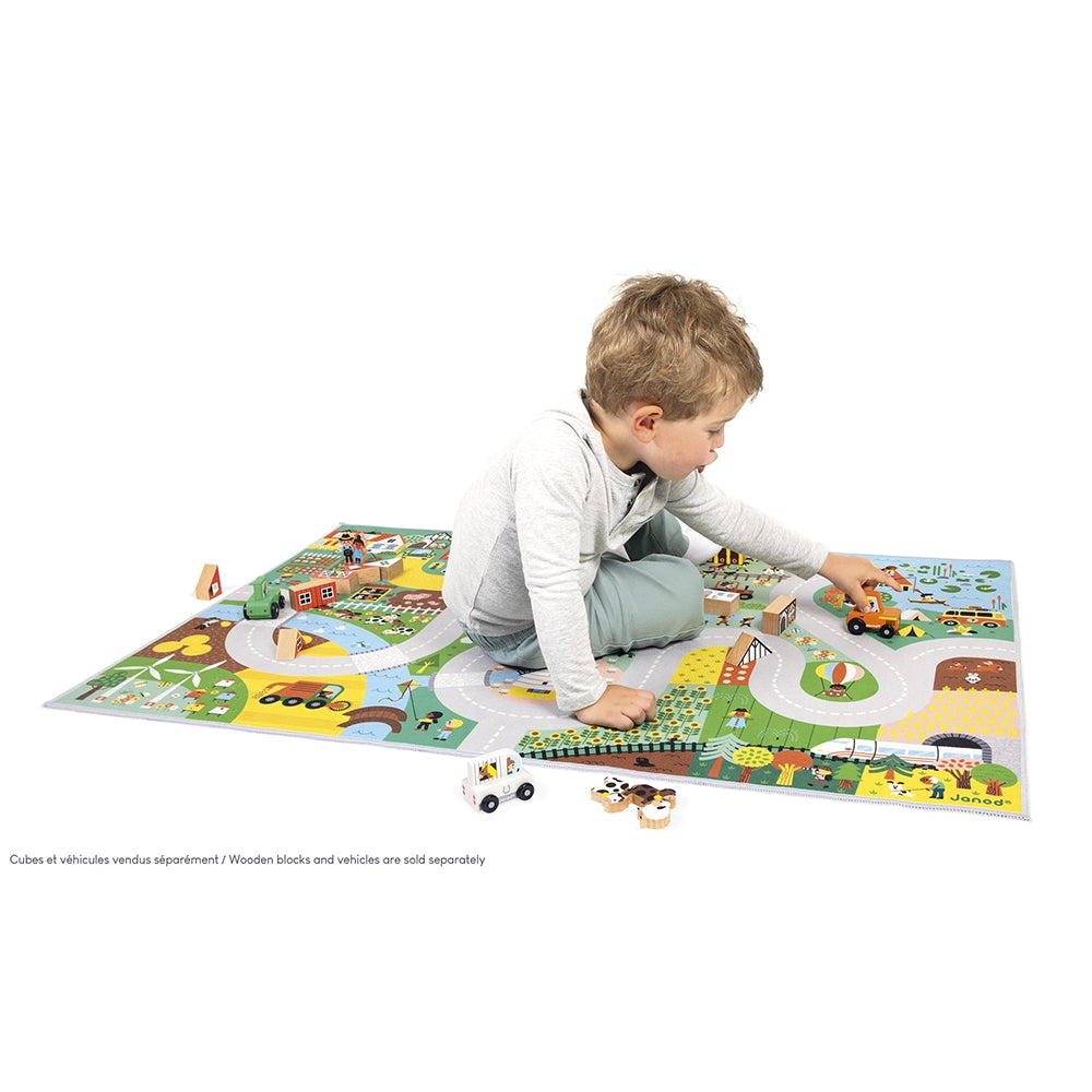 Child playing with a colorful toy mat featuring roads and vehicles on a white background.