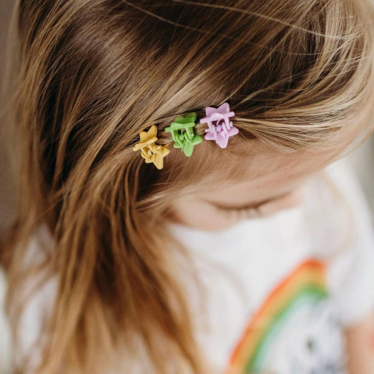 Close-up of a child's hair with colorful flower-shaped hair clips.