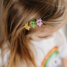 Close-up of a child's hair with colorful flower-shaped hair clips.