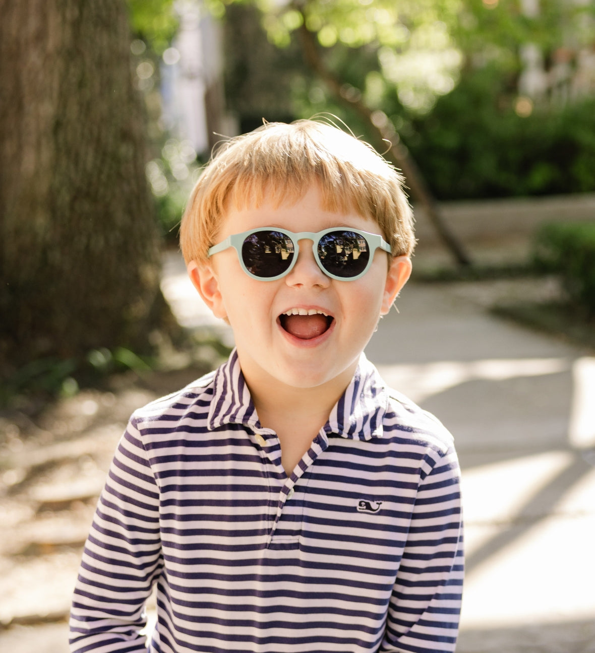 Child wearing sunglasses and a striped shirt outdoors