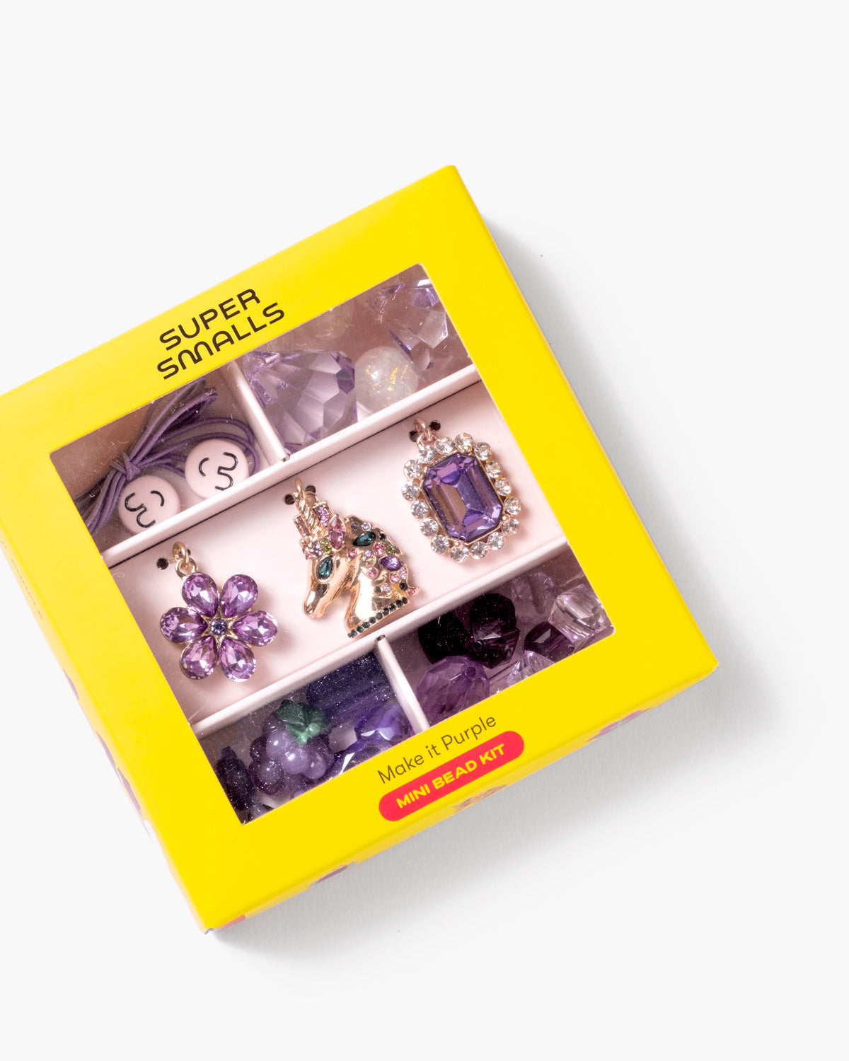 A yellow Super Smalls 'Mozzi's Purple' bead kit box, shown at an angle on a white background. The box has a clear window displaying various purple and lavender beads, crystals, and a small horse-shaped bead.