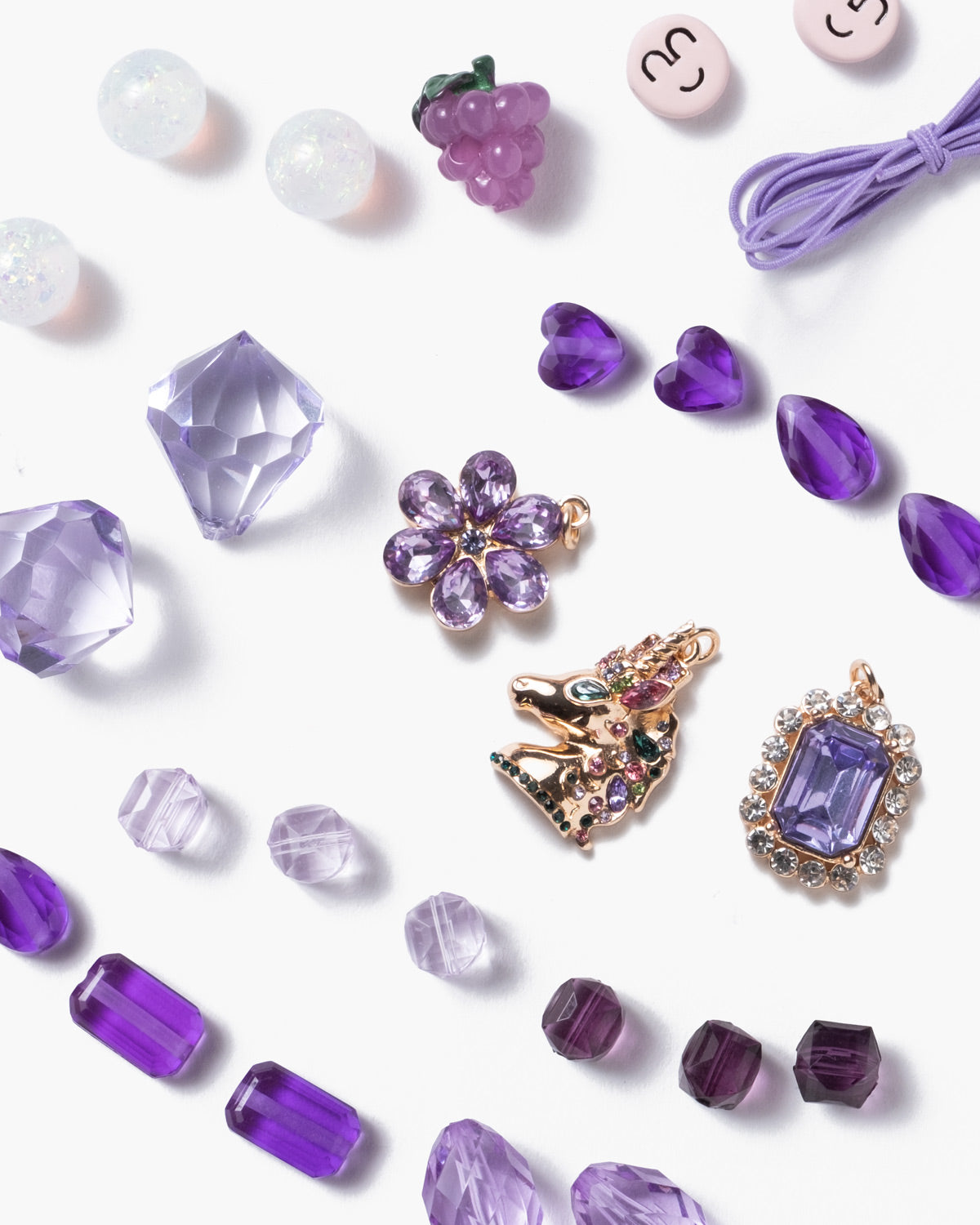 Purple jewelry pieces including brooches and beads on a white background