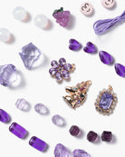 Purple jewelry pieces including brooches and beads on a white background
