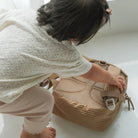 Child playing with a woven basket on a white floor