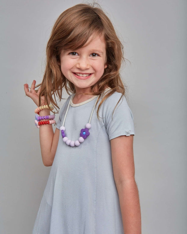 Young girl in a gray dress with jewelry on a gray background