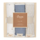 A boxed set of three baby burp cloths from Crane Baby, neatly folded and presented in a light beige gift box with a central label. The cloths are in soft neutral tones: one off-white with delicate gray botanical prints, one dusty blue, and one light beige with white dotted patterns.