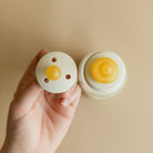 Two small round containers with a yellow substance on a beige background