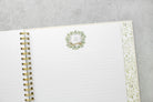 White planner with gold binding on a gray surface