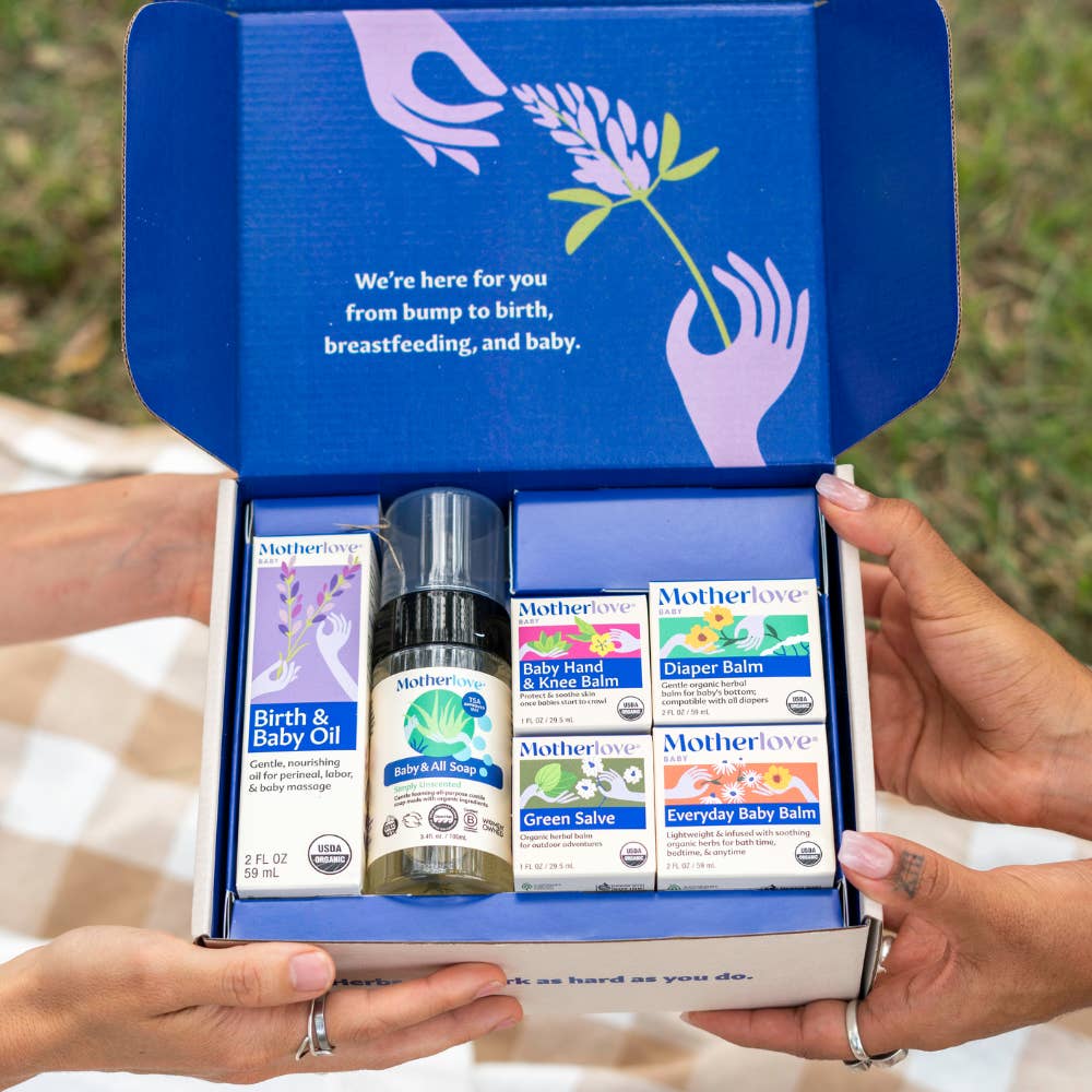 Open box of Motherlove baby care products held by hands with a grassy background.