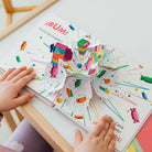 Colorful children's book with pop-up elements on a white surface.