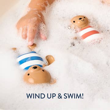 Bath toys with a child's hand in bubbles, featuring text 'Wind Up & Swim!'.