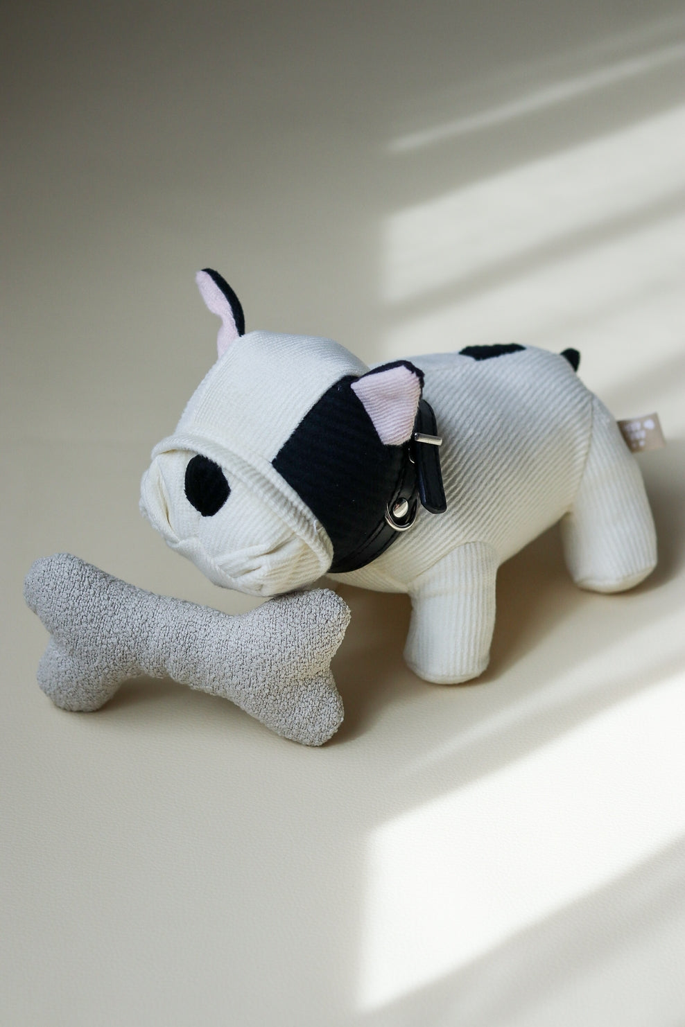 Stuffed animal dog with a bone toy on a light surface