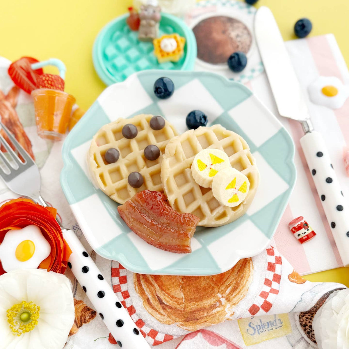 Miniature waffles with toppings on a checkered plate with a yellow background