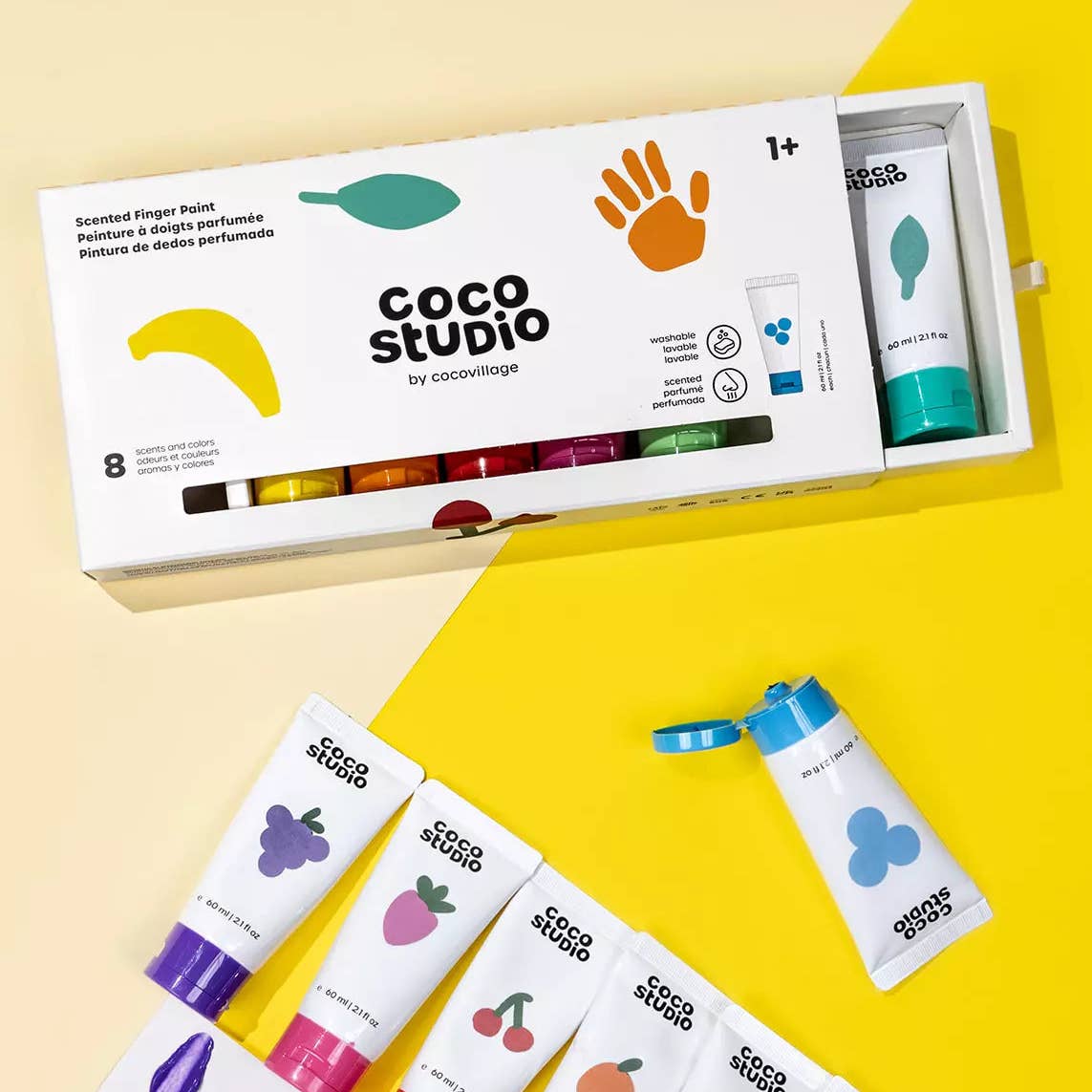 Coco Studio Scented Finger Point set in a white box with a sliding drawer, shown on a split cream and bright yellow background with several white tubes featuring colorful fruit illustrations.
