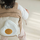 Person wearing a baby carrier with a unique design on a neutral background