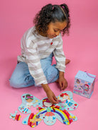 Child playing with a puzzle on a pink background