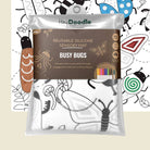 Hey Doodle Reusable Silicone Sensory Mat 'Busy Bugs' in its clear plastic packaging, featuring a white mat with black bug outlines and a brown label, set against a white background with black bug illustrations.