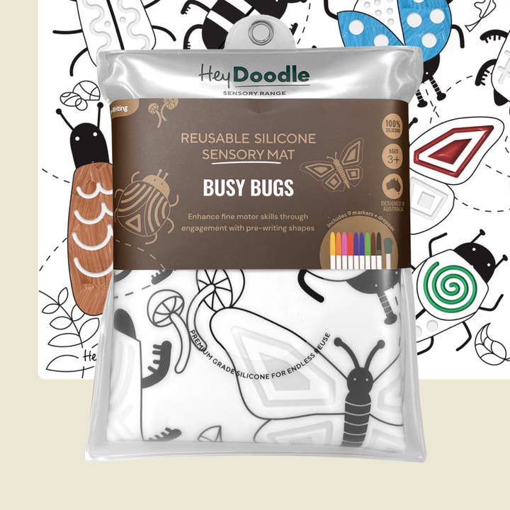 Hey Doodle Reusable Silicone Sensory Mat 'Busy Bugs' in its clear plastic packaging, featuring a white mat with black bug outlines and a brown label, set against a white background with black bug illustrations.