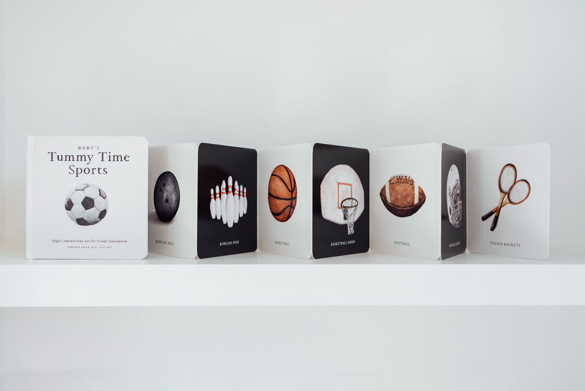 Row of books with sports-themed illustrations on a white shelf
