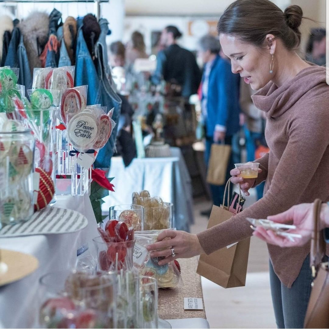 Woman shopping at a market stall with various products on display.