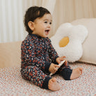 Child in floral pajamas sitting on a couch with a white pillow